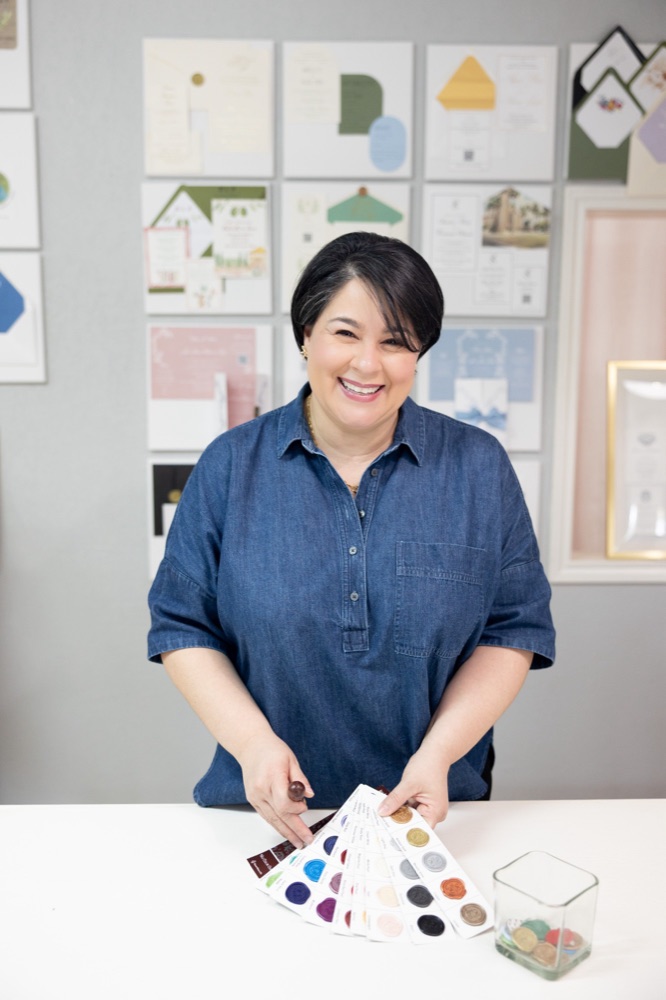 Clara, the designer behind For the Love of Paper, smiling beside paper samples
