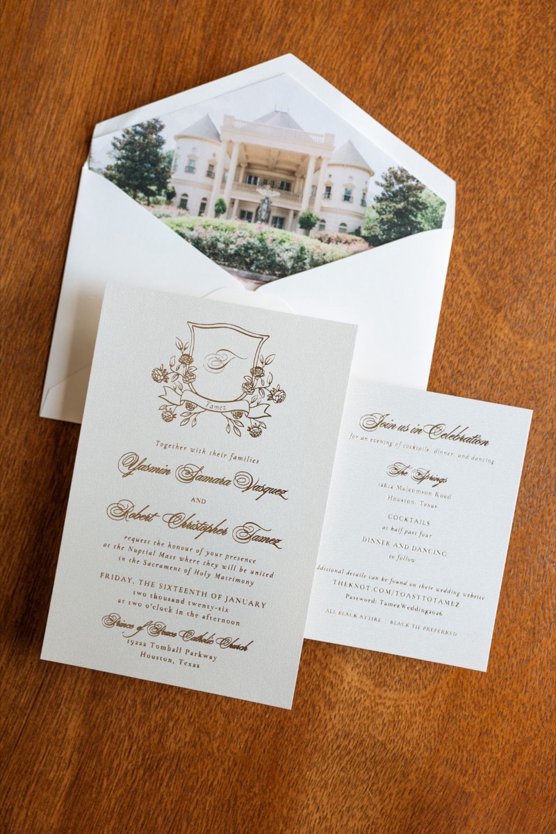 Wedding invitation suite with a gold crest beside a building-view envelope