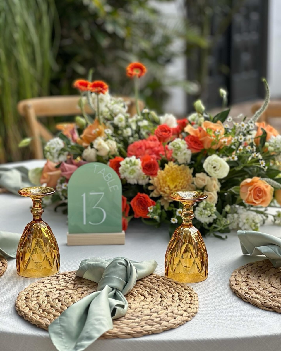 Table styled with orange florals, amber glass and greenery