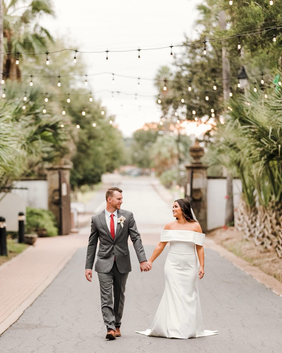 Couple walking hand in hand down a tree-lined street
