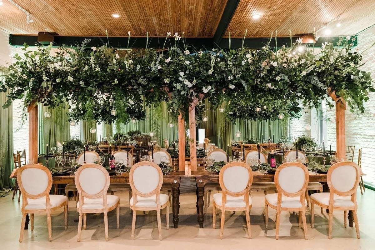 Long reception tables set under a canopy of greenery and lights