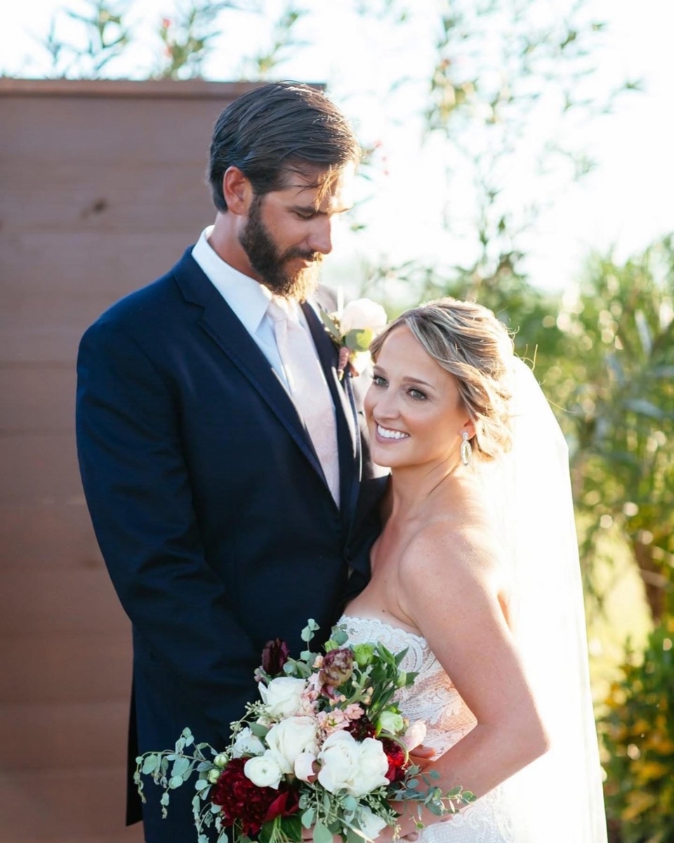 Couple posing together with a bouquet outdoors